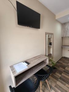 a room with a table and a tv on a wall at Hotel Boutique Porá Iguazú in Puerto Iguazú