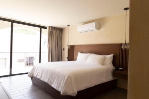 a bedroom with a white bed with a large window at Moreira Hotel Boutique in Mérida