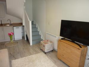 a living room with a flat screen tv and a staircase at Eastern Lodge 11B in Lymington