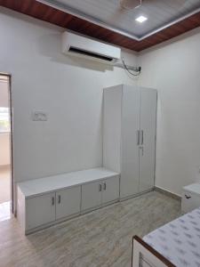 a kitchen with white cabinets and a white wall at Kohli Farms in Gof