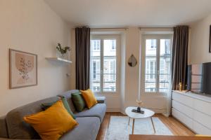 a living room with a couch and two windows at Cœur de Fontainebleau in Fontainebleau