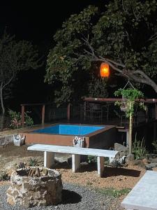 a white bench in front of a pool at night at Chalé Vista da Serra in Pedro II