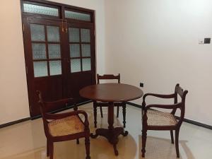 a wooden table and two chairs and a table and a door at 7C Villa in Galle