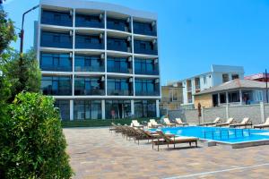 a hotel with a pool and lounge chairs and a building at Hotel Zich in Kobuleti