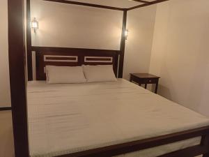 a bedroom with a large bed with a wooden headboard at 7C Villa in Galle