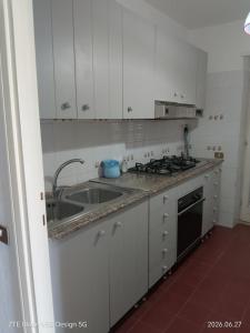 a white kitchen with a sink and a stove at FLOWER-House in Anzio