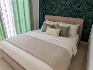 a bedroom with a large white bed with green curtains at AYA Stay in Andoharanofotsy