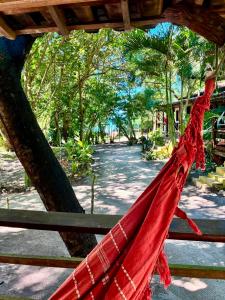 a red hammock hanging from a wooden fence at Mar de Moreré in Cairu