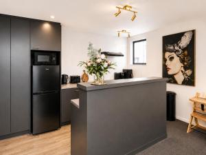 a kitchen with a black refrigerator and a counter with flowers at Cathedral Junction Apartments in Christchurch