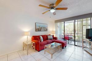 a living room with a red couch and a ceiling fan at Shorewalk Villa in Bradenton