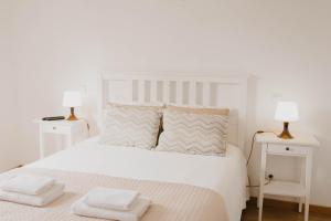 a white bedroom with a white bed with two lamps at Casa do Foral by Lethes Legacy in Ponte de Lima