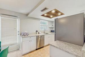 a kitchen with white cabinets and a stainless steel refrigerator at Gertie's Coconut House in Holmes Beach +19 photos