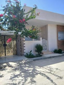 a house with a gate and a tree with pink flowers at Dar Si Lamin 2 in Kelibia