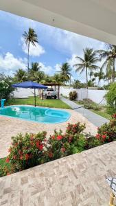 a swimming pool in a yard with palm trees at Casa Estrela Azul in Pitimbu