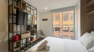 a bedroom with a bed and a tv and a window at Parque de La 93 - Elite Flats in Bogotá