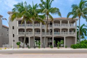 a large white building with palm trees in front of it at White Cap Condo B201 by Sun Palace Vacations in Fort Myers Beach