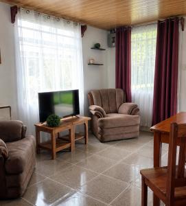 a living room with two chairs and a flat screen tv at Arenal Rental CASA PALMERA UNO in Arenal