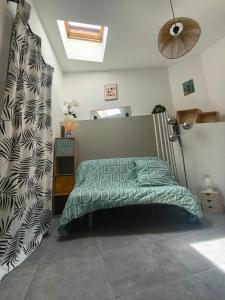 a bedroom with a bed with a green comforter at Cozy studio - proche Cité de Carcassonne in Couffoulens