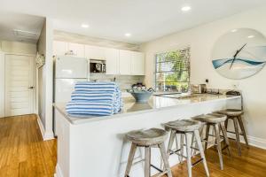 a kitchen with white cabinets and a counter with stools at Sandy's Getaway in Anna Maria