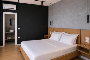 a bedroom with a white bed and a black wall at NOOR Boutique Hotel in Koplik