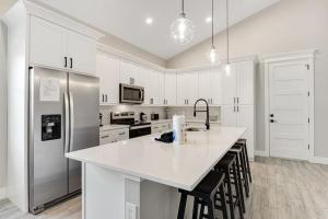 a kitchen with white cabinets and a stainless steel refrigerator at Friendly City Fun in Bradenton +27 photos