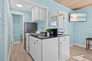 a kitchen with blue walls and white cabinets at Parrot Beach Cottages Suite #4 in Siesta Key +15 photos