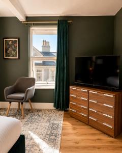 a bedroom with a television and a chair and a window at The Promenade House in New Brighton