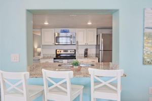 a kitchen with white chairs and a counter top at Bungalow A in Bradenton Beach +23 photos