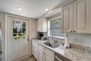 a kitchen with white cabinets and a sink and a window at Bungalow B in Bradenton Beach +20 photos