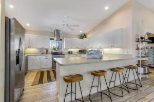 a kitchen with white cabinets and a large counter with stools at Sundance Cottage in Anna Maria +27 photos