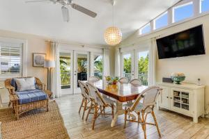 a dining room with a table and chairs and a tv at Sundance Cottage in Anna Maria