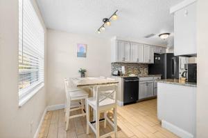 a kitchen with white cabinets and a table and chairs at Holmes Beach Bungalow - A in Holmes Beach