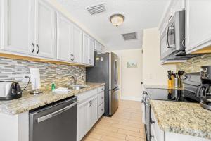 a kitchen with white cabinets and a black refrigerator at Holmes Beach Bungalow - A in Holmes Beach +37 photos