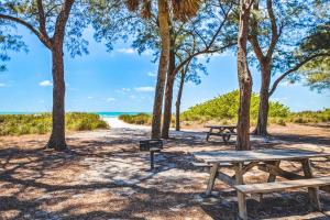 two picnic tables on the beach with trees at Breezy Bungalow A and B in Bradenton Beach