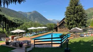 a swimming pool with a house and mountains in the background at Hotel Petit Lacreu in Salardú