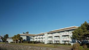 a large white building with balconies and palm trees at The Marina Inn on San Francisco Bay in San Leandro