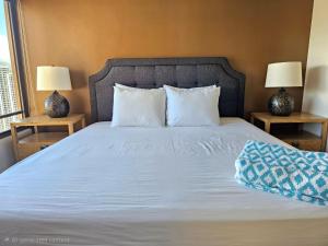 a bed with white sheets and two lamps on two tables at Discovery Bay 3517 in Honolulu +15 photos