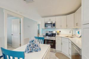 a kitchen with white cabinets and a table and chairs at Playa Casanas South in Holmes Beach +18 photos