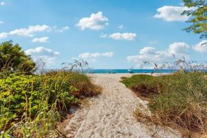 a path to the beach with the ocean in the background at Playa Casanas North in Holmes Beach