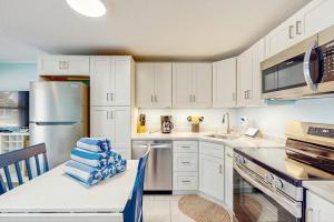 a kitchen with white cabinets and a sink and a refrigerator at Playa Casanas North in Holmes Beach +22 photos