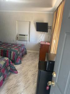 a room with two beds and a refrigerator and a tv at Terrace Motel in Natchez