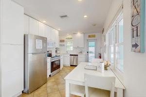 a white kitchen with a table and a refrigerator at Sea's The Day in Anna Maria