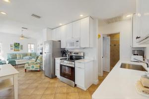 a kitchen with white cabinets and appliances and a living room at Sea's The Day in Anna Maria +8 photos
