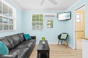 a living room with a black leather couch and a table at Parrot Beach Cottages Suite #2 in Siesta Key