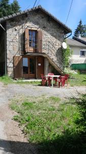 a stone house with red picnic tables in front of it at Maison rustique in Devesset