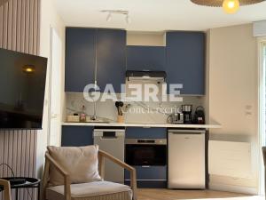 a kitchen with blue cabinets and a chair in a room at GC - Les Flots in Wissant
