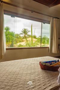 a bedroom with a large window with a view of a beach at GuestHouse Casa da Aroeira in Búzios