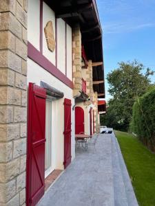a building with red doors and a table on a patio at L'Annexe de l'Etape Basque in Bidart