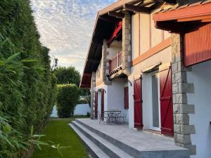 a building with red doors and a table on a patio at L'Annexe de l'Etape Basque in Bidart