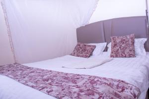a bed with white sheets and pink pillows at Amber Apartments G1 Kitengela in Athi River